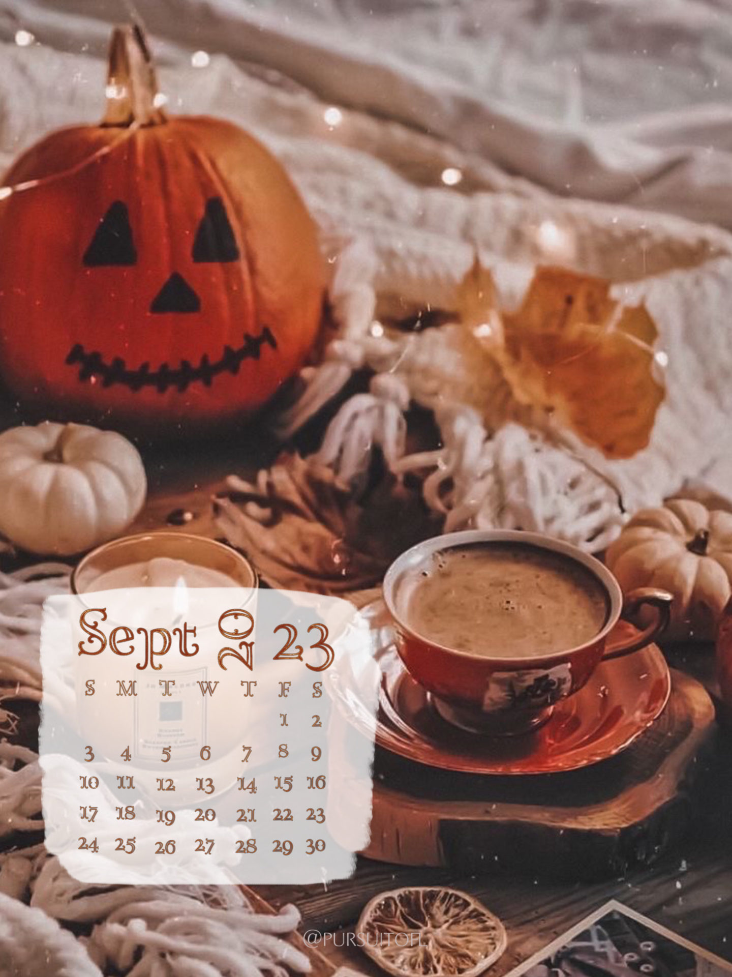 Tablet wallpaper with cozy fall setting with candle, warm drink, fairy lights, pumpkin on a bed, and September 2023 calendar