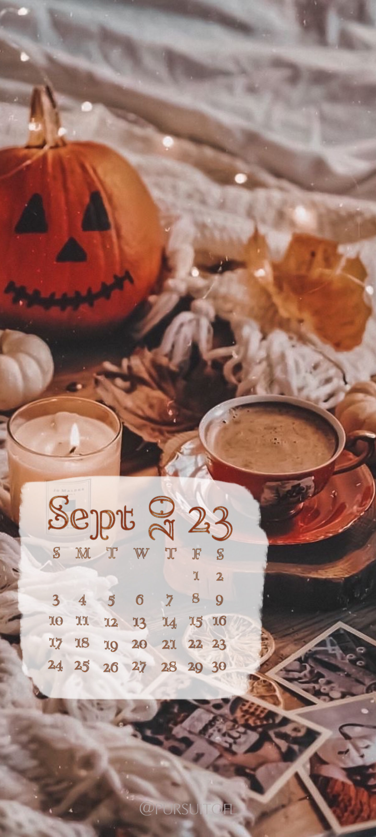Phone wallpaper with cozy fall setting with candle, warm drink, fairy lights, pumpkin on a bed, and September 2023 calendar