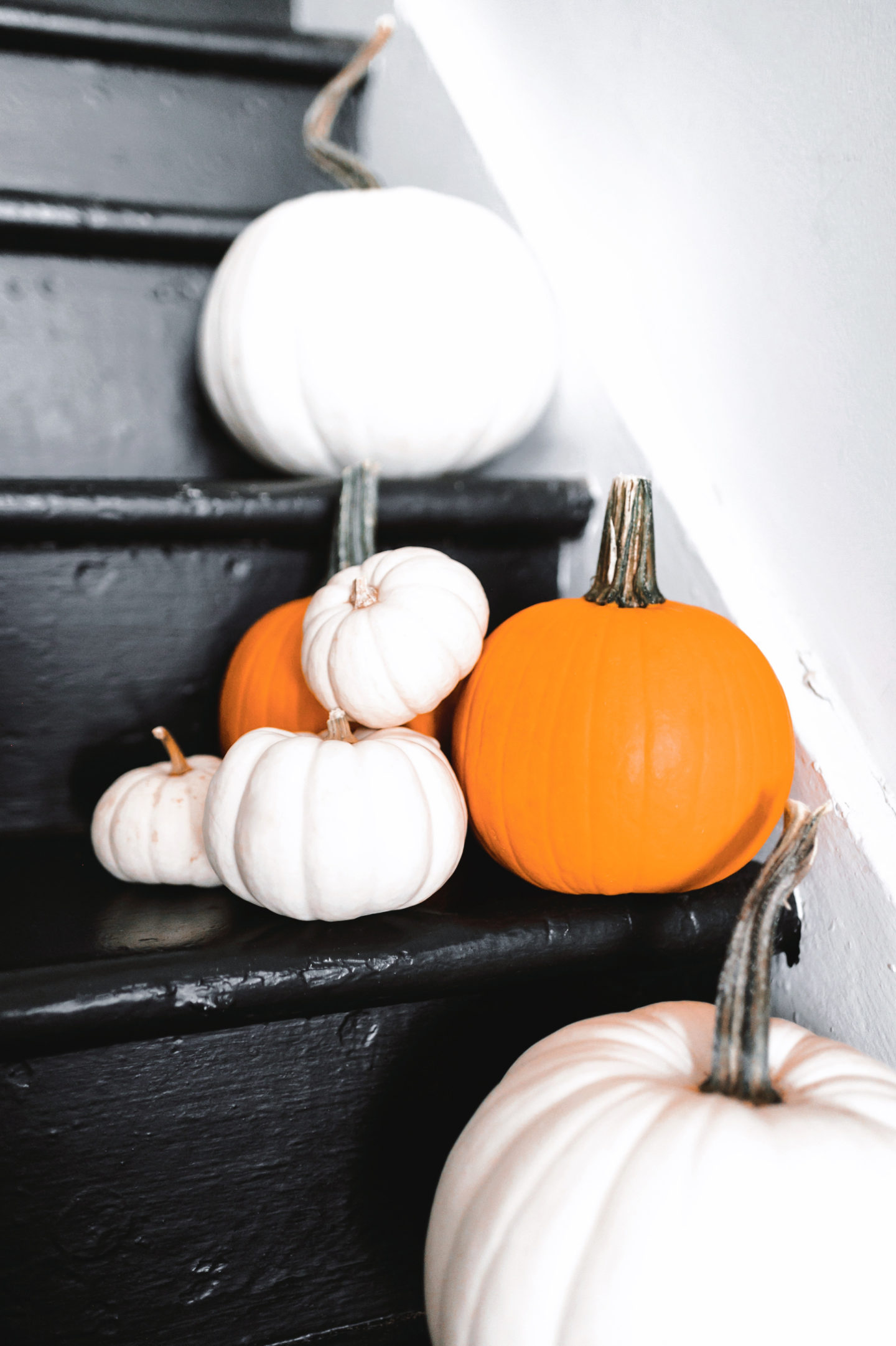 Fall home decor, orange and white pumpkins of different sizes on a black staircase