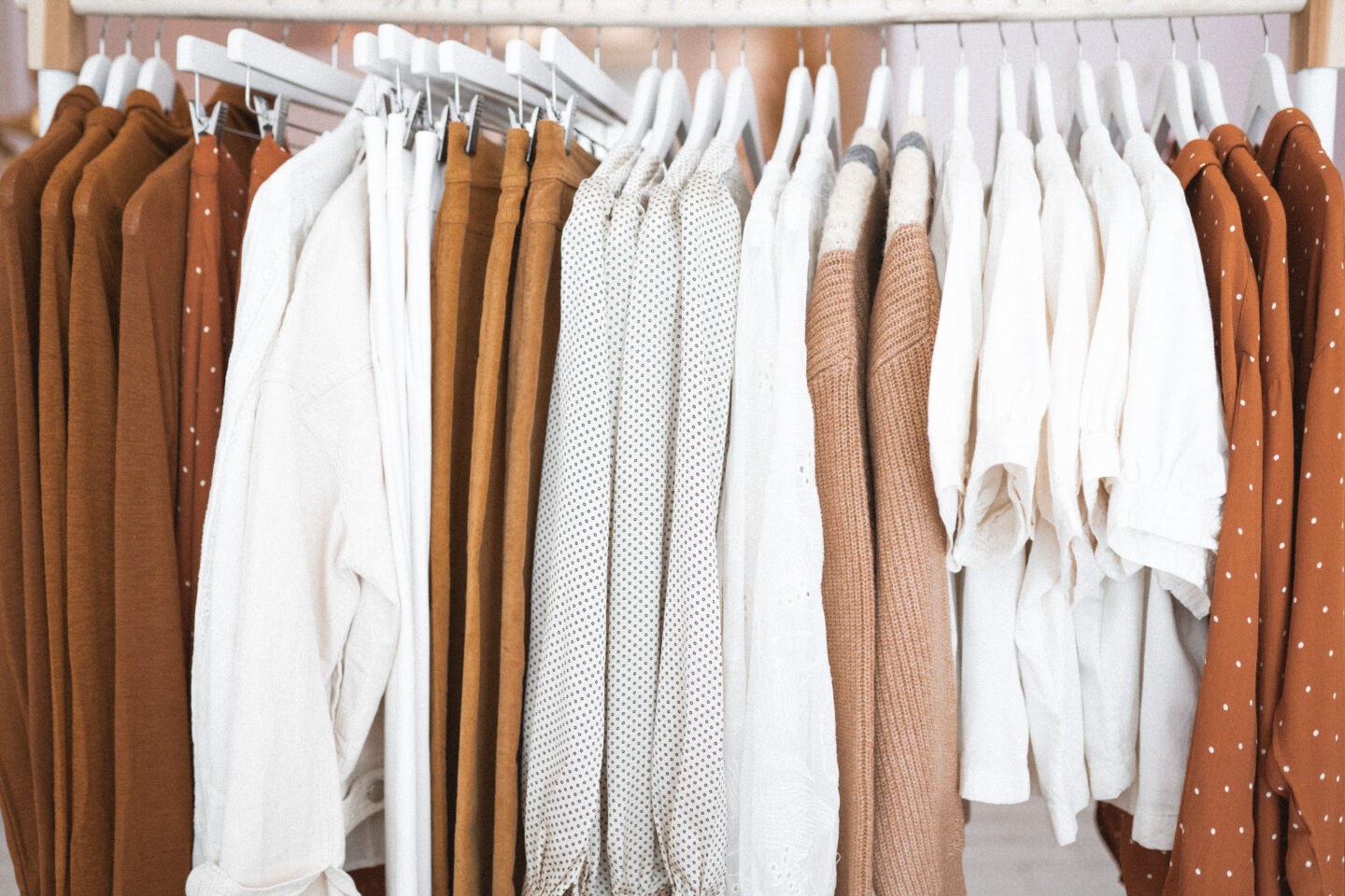 Warm tones, tops and pants hanging on a clothing rack
