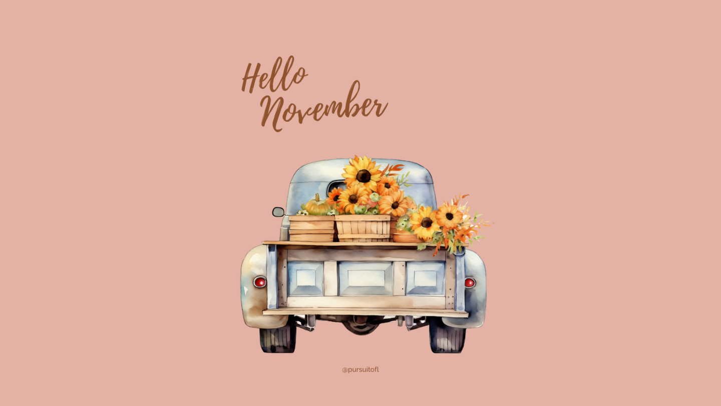 A soft blush pink desktop wallpaper with a vintage blue truck filled with sunflowers and pumpkins in wooden crates, with the words 'Hello November' written in a warm, cursive font above.