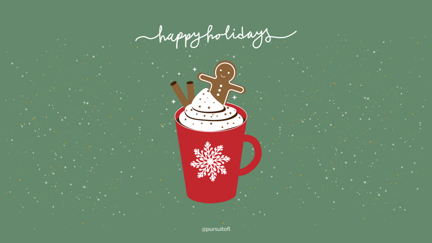 Holiday mug of hot cocoa topped with whipped cream, a gingerbread cookie, and cinnamon sticks on a green festive desktop background.