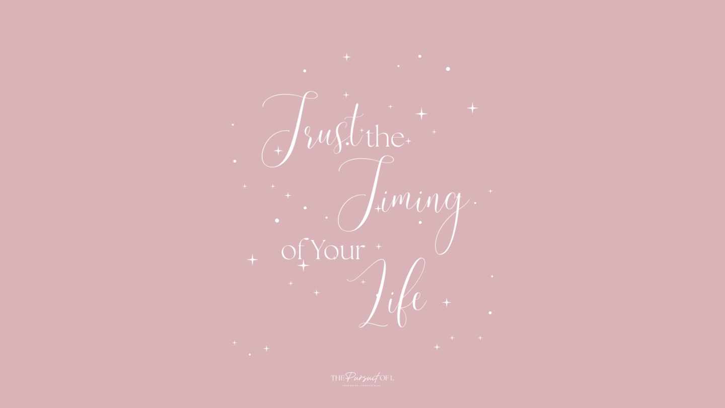 Soft pink background with scattered white stars and dots, featuring elegant white script that reads “Trust the Timing of Your Life.” Minimal, calming design. Desktop wallpaper.