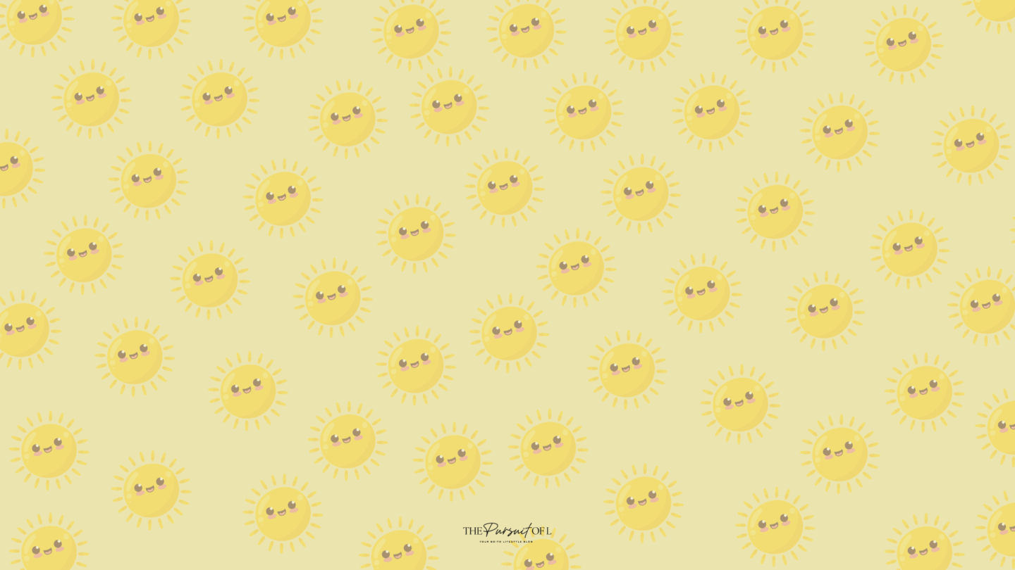 Pale yellow background covered in repeating illustrations of cheerful, cartoon-style yellow suns with smiling faces and rosy cheeks. Desktop wallpaper.